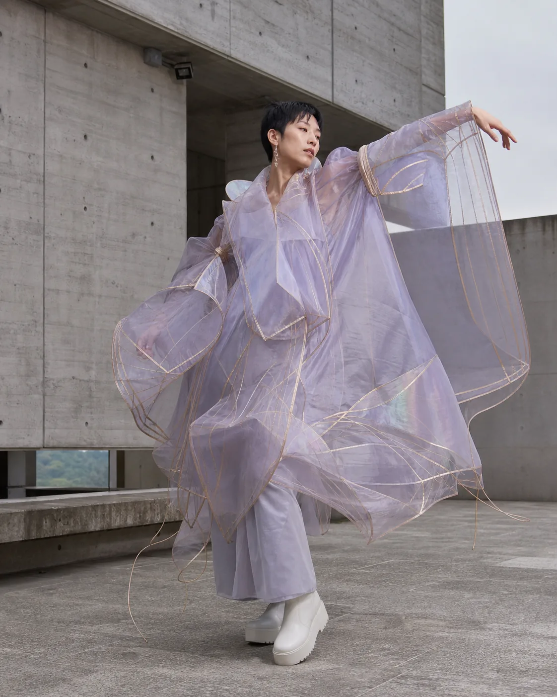 Person in a translucent experimental wearable at a concrete museum